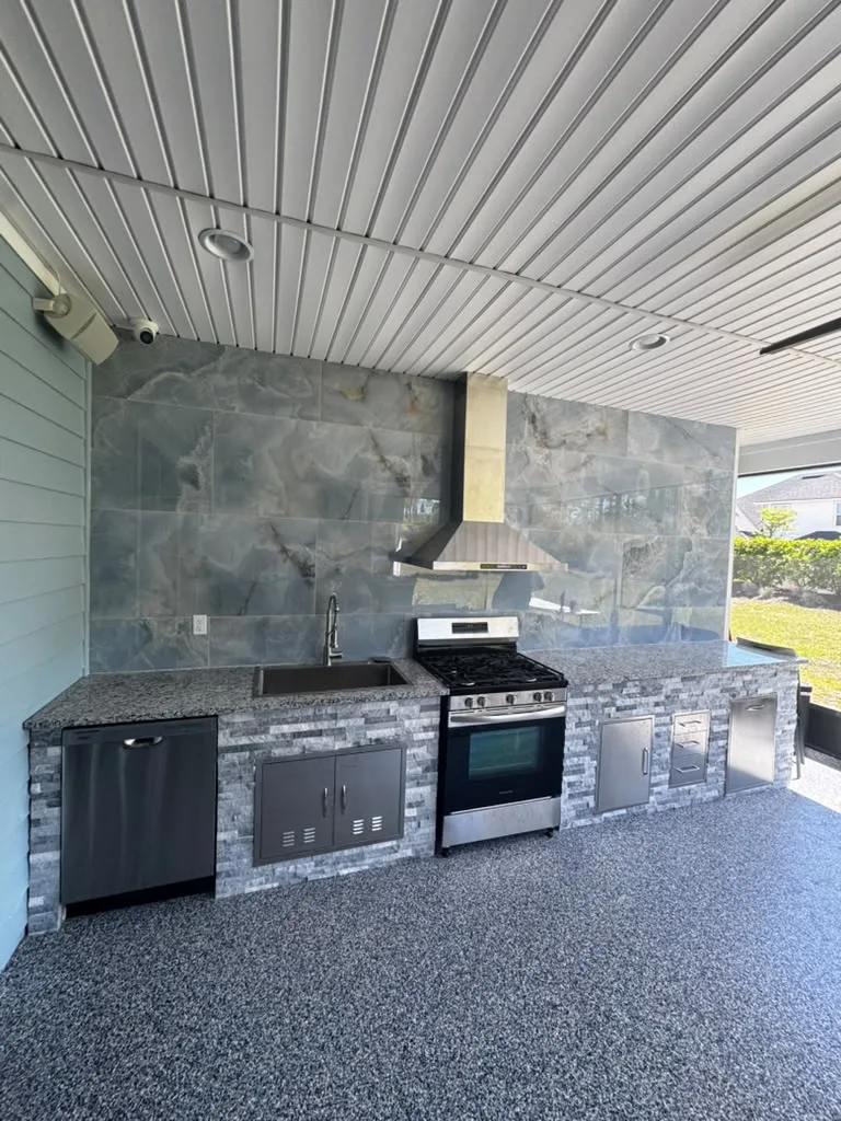 The patio after installation, with stone wall, grill, hood and cabinetry