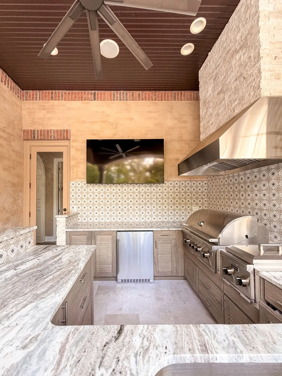 Stone-clad summer kitchen with granite countertops and stainless steel grill
