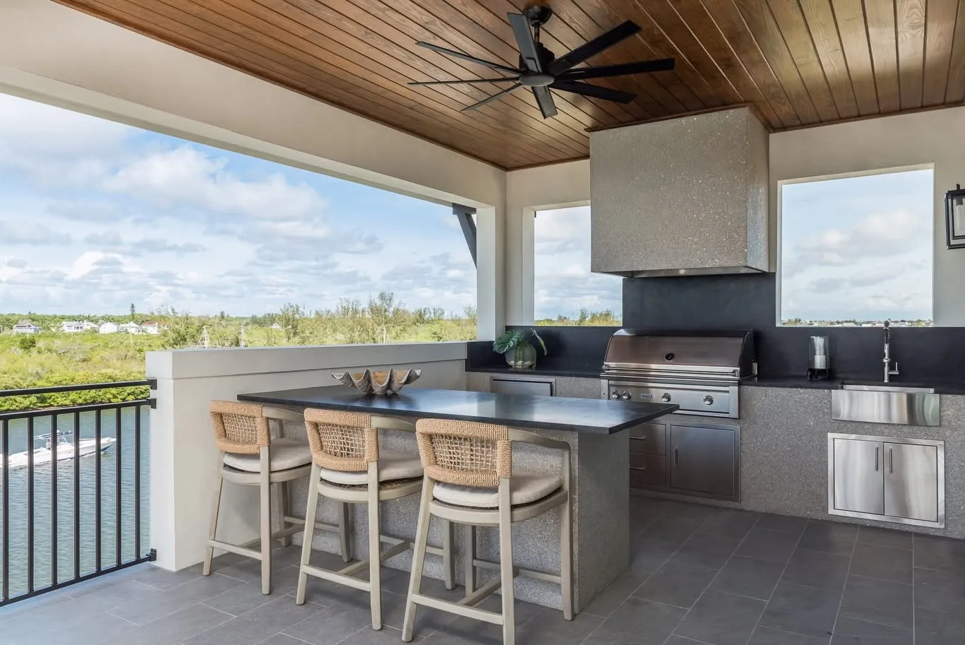 Covered outdoor kitchen with island seating overlooking the water